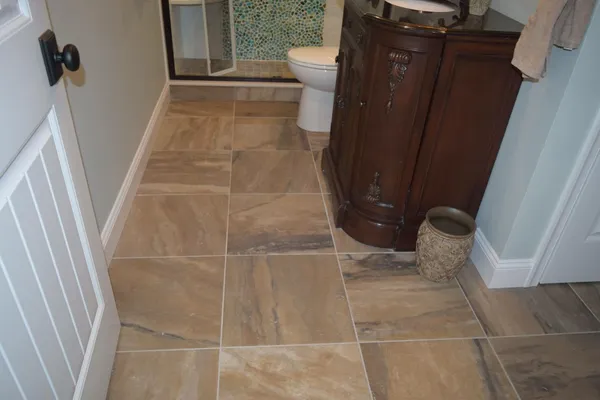 Bathroom remodel with a large-format tile floor and a carved wood vanity