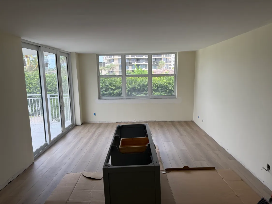 Empty living room with new wood-look plank flooring and a sliding door out to the balcony