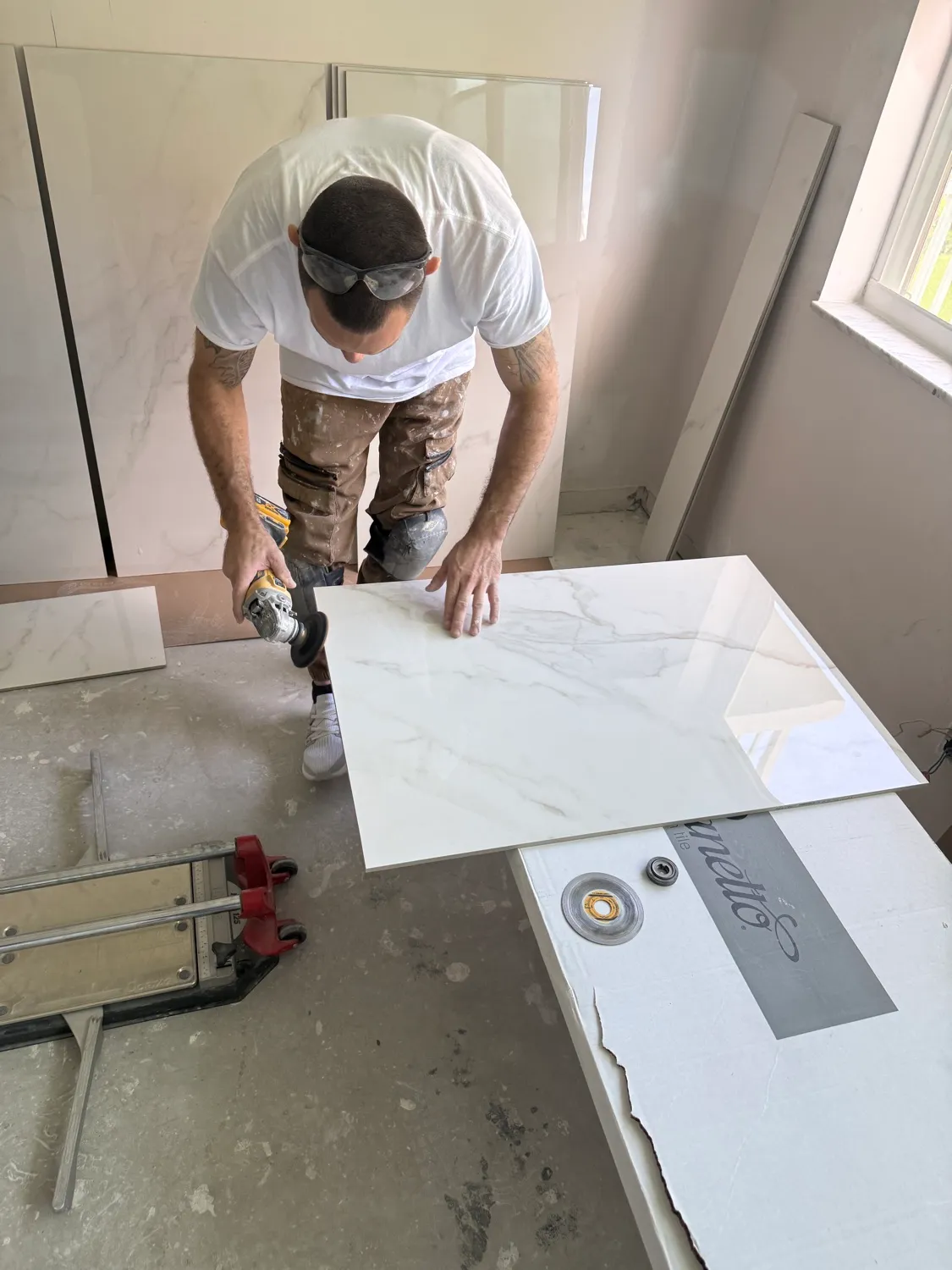 Tile setter grinding the edge of a large marble-look porcelain tile