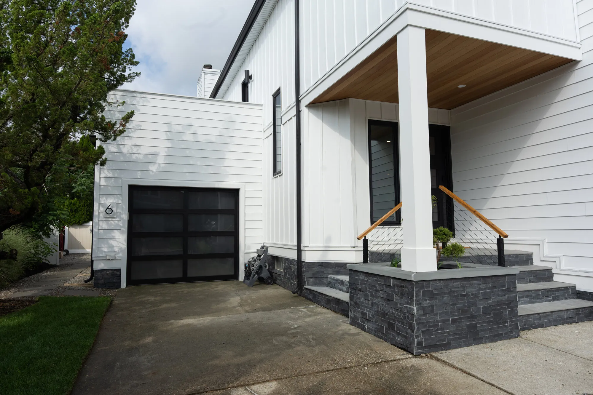Coastal home driveway with glass garage door and stone-clad entry, the salt-rated build Seaboard does on Singer Island