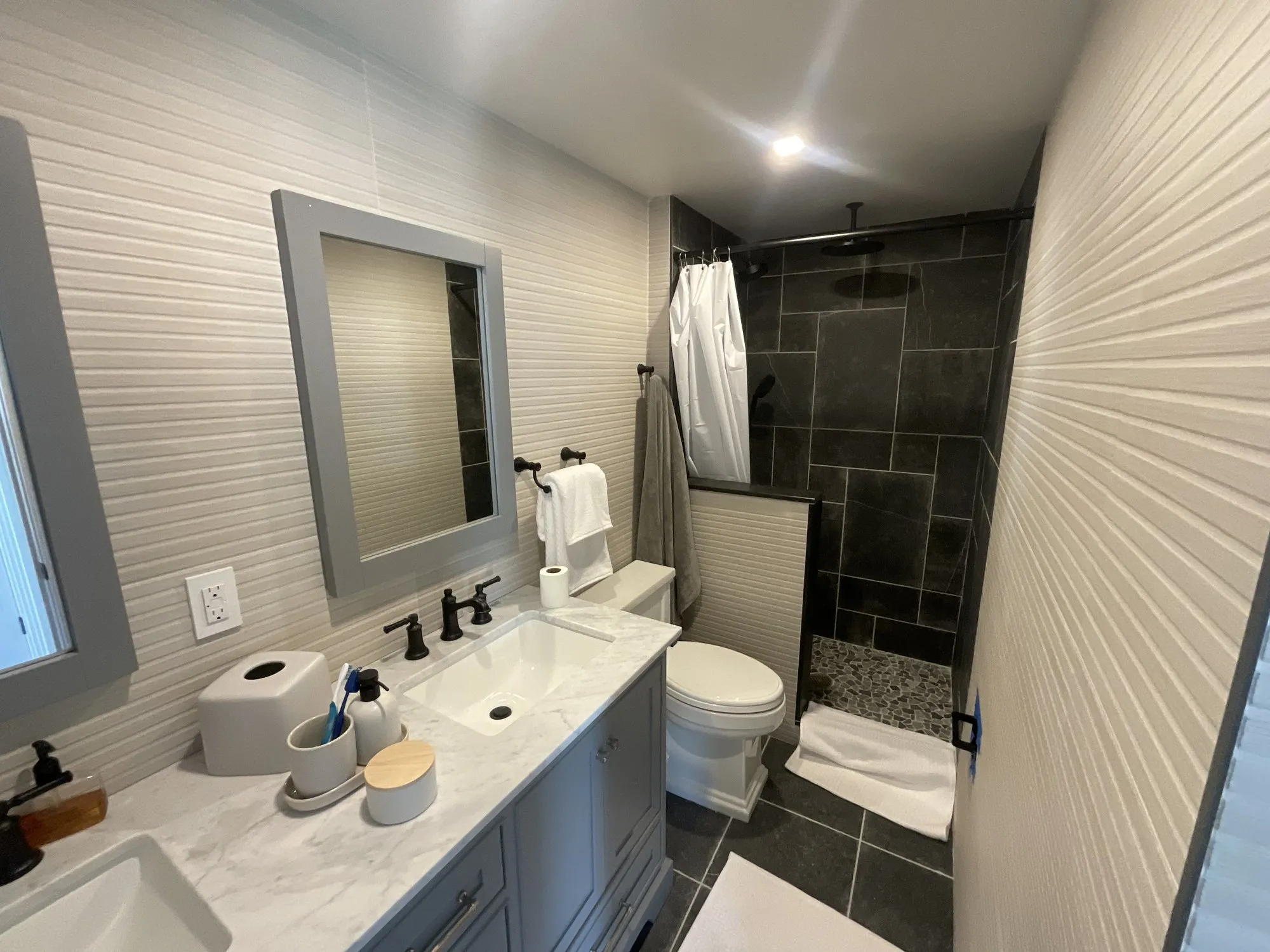 Bathroom with a white vanity, slate-tile shower, and textured wall tile