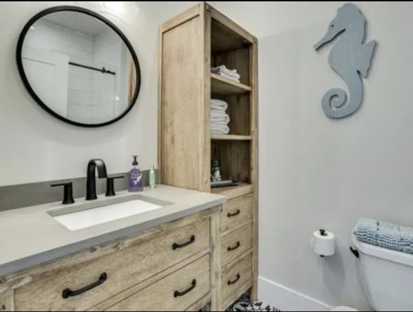 Bathroom vanity with a round mirror, wood cabinetry, and seahorse decor