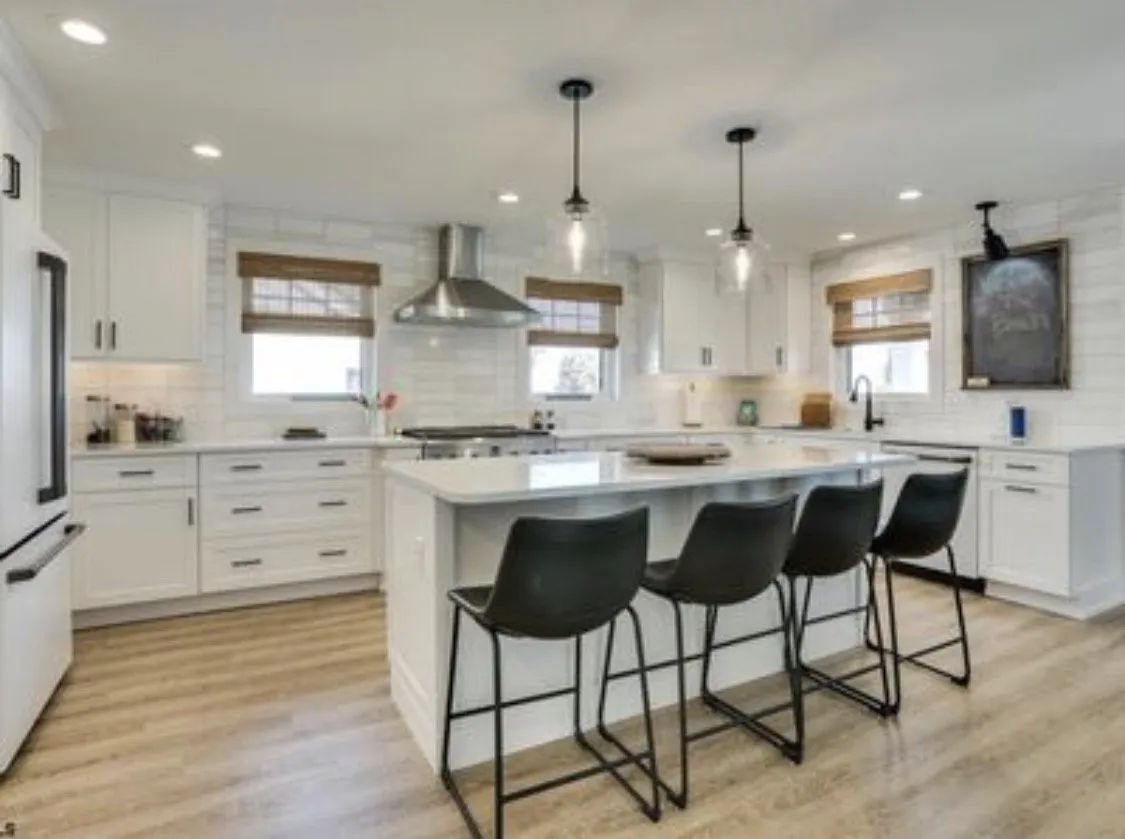 White kitchen with a large island, black counter stools, and pendant lights in Margate, NJ