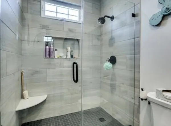 Walk-in shower with wood-look tile, a glass door, and a built-in niche