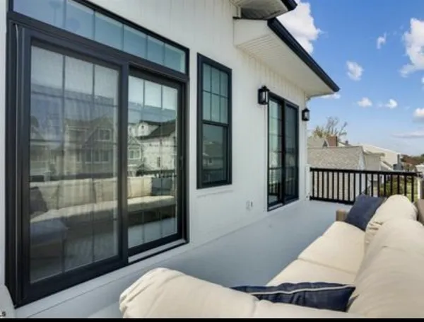 Upper balcony with black-framed sliding doors and outdoor seating
