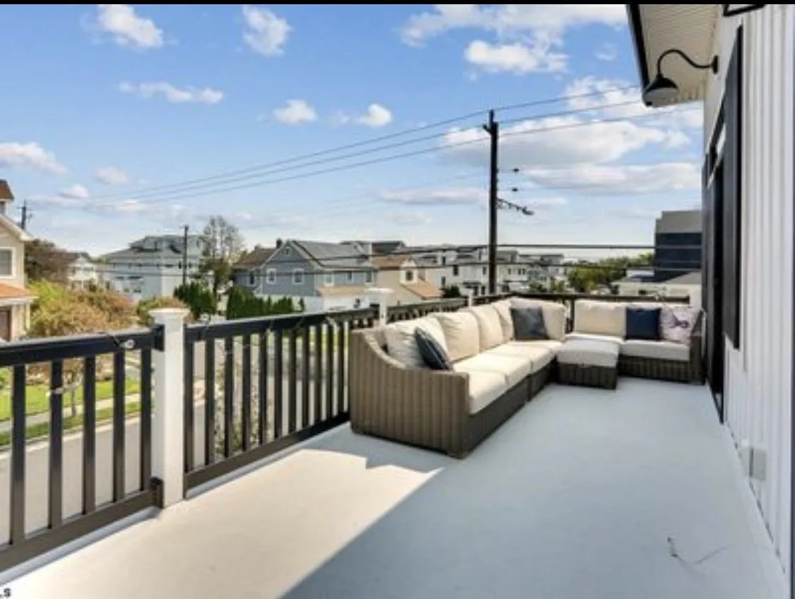 Second-floor deck with wicker sectional seating and neighborhood views