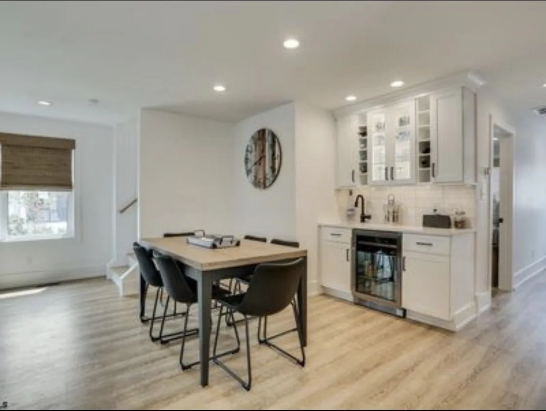 Dining area with a black-legged table and a white wet bar with wine fridge