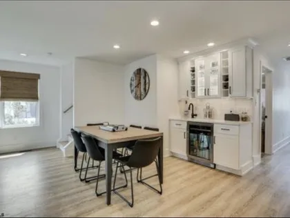 Dining area with a black-legged table and a white wet bar with wine fridge