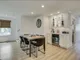 Dining area with a black-legged table and a white wet bar with wine fridge