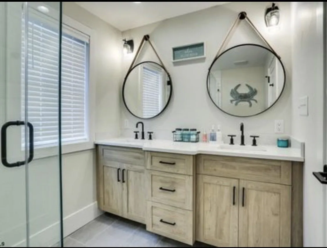 Bathroom double vanity with round rope-hung mirrors and wood cabinets