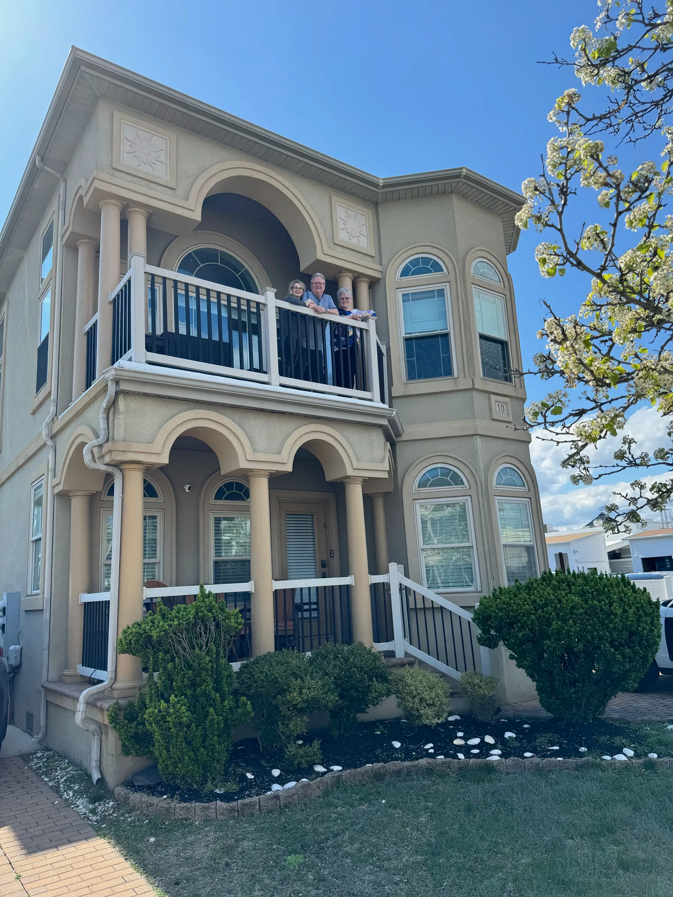 Two-story stucco home with arched columns, a second-floor balcony, and a covered front porch
